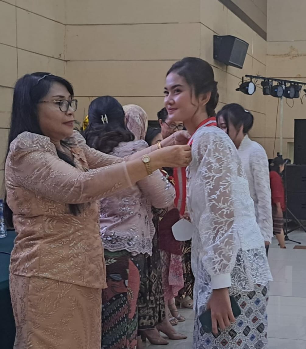 SELAMAT: Kepsek SMKN 3 Manado saat mengalungkan medali tanda kelulusan kepada siswa.